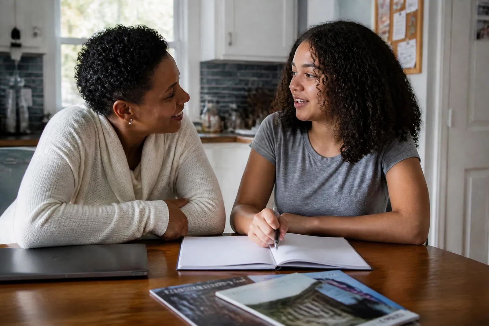 A parent and high school student planning together at a kitchen table